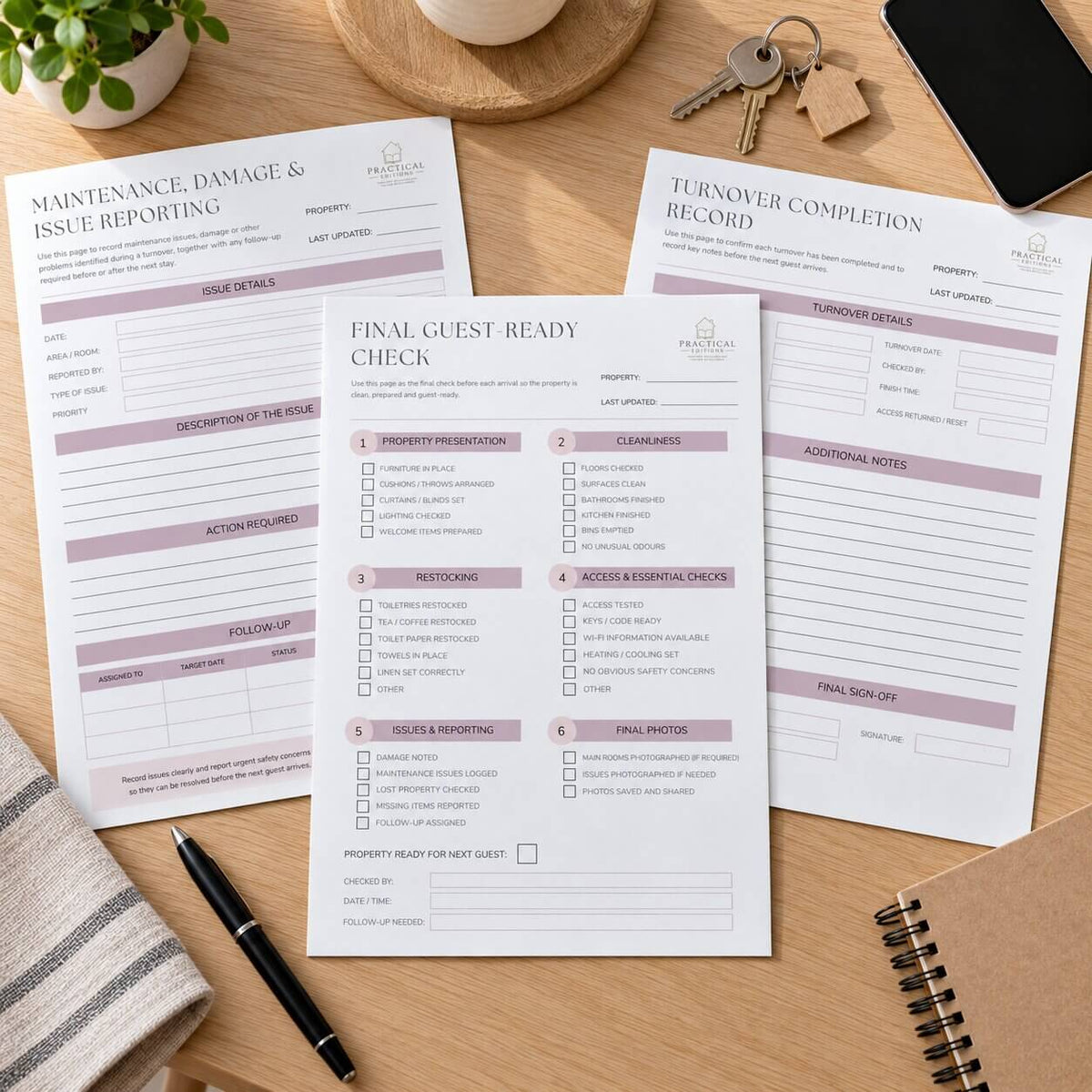 Three printed property management paperwork sheets arranged on a wooden desk with a pen, keys, phone, and notebook nearby. The sheets include forms such as maintenance/damage/issue reporting, final guest ready check, and turnover completion record, with a visible property management logo at the top.