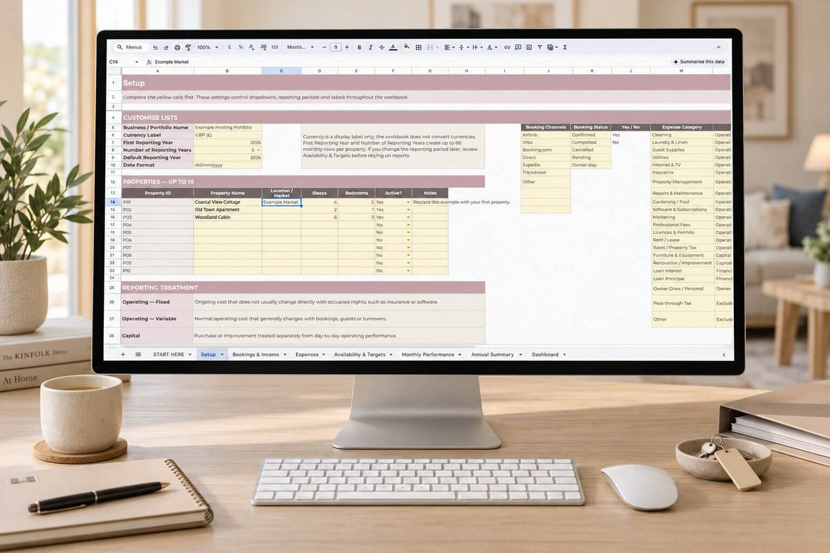 A desktop computer monitor on a wooden desk displaying a spreadsheet template, surrounded by a keyboard, mouse, mug, notebook, and books in a bright, modern home office setting.